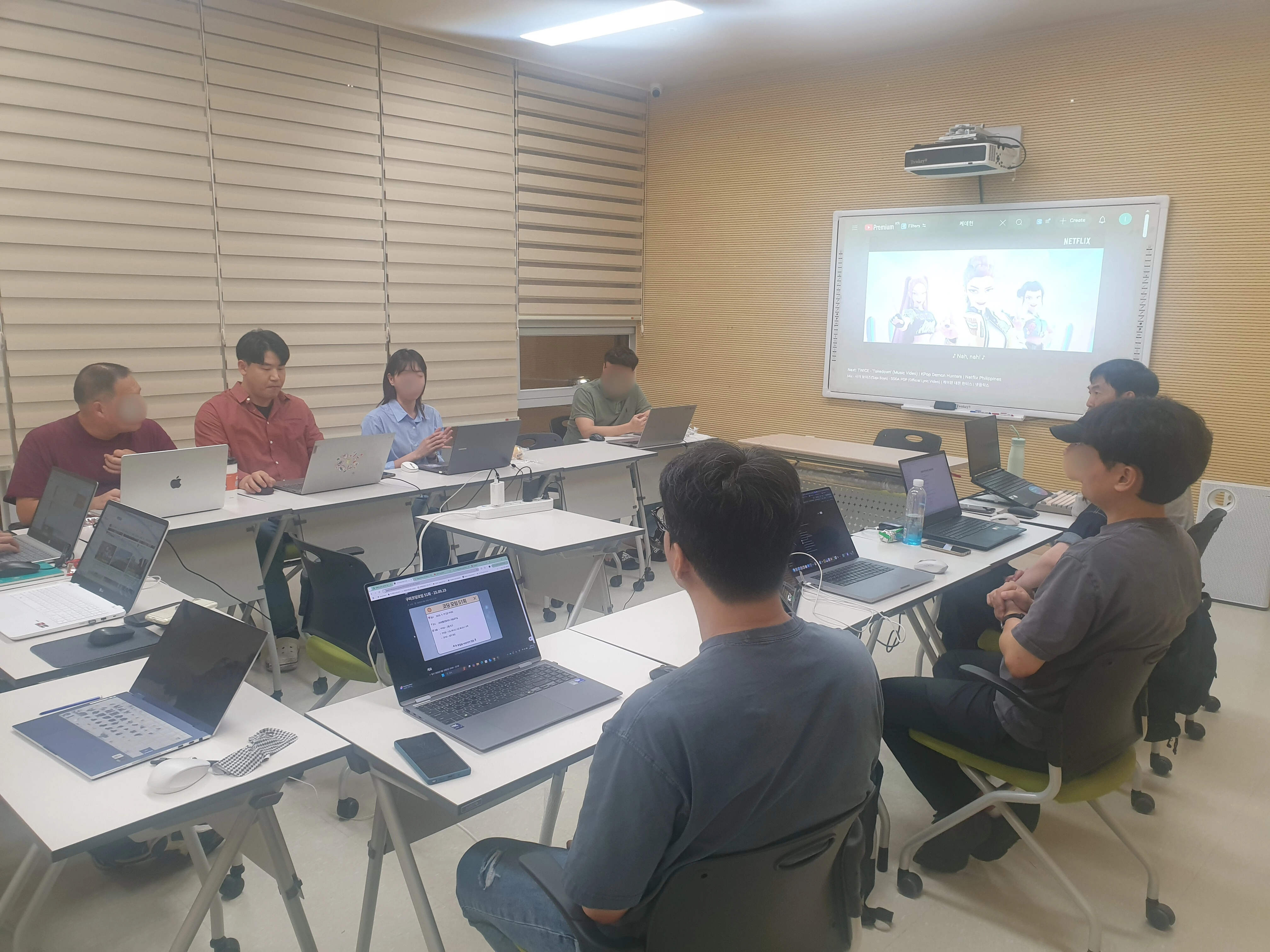 여러 사람이 노트북과 스크린을 보며 함께 작업하는 네온랩스 활동 장면
